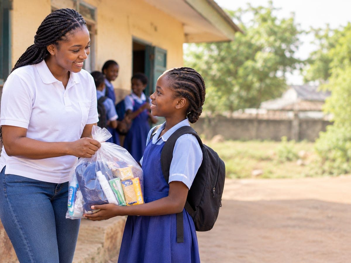 A JTAH volunteer handing a bag of essentials to a schoolgirl